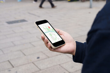 Woman with baggage in downtown city street searching location in map application online on smart phone using GPS navigating.