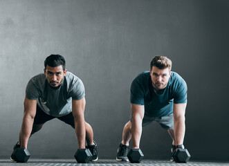 Poster - Were ready, are you. Full length portrait of two handsome young male athletes working out with dumbbells side by side against a grey background.