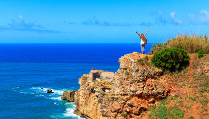 Wall Mural - Woman with outstretched arms enjoying atlantic ocean panoramic view- Portugal, Nazare