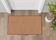 Blank brown door mat on the floor at home. Welcome mat with copy space for your text. Doormat mock up. Carpet at entrance for wiping dirty shoes. Mockup. 3D Rendering.
