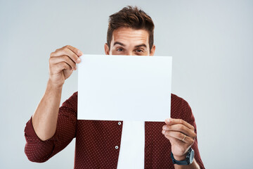 Poster - Can you see it. Portrait of a cheerful young man holding and displaying a poster while standing against a grey background.