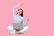 © New Africa - Happy woman with laptop pointing at something on pink background, space for text