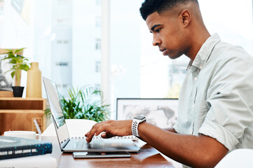 Canvas Print - He wont stop until his clients get what they want. a young businessman using a laptop at his desk in a modern office.