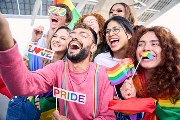 Diverse group of happy young people taking funny selfie for social media celebrating gay pride festival day. Lgbt community concept cheerful friends outdoors. Generation z enjoy party.