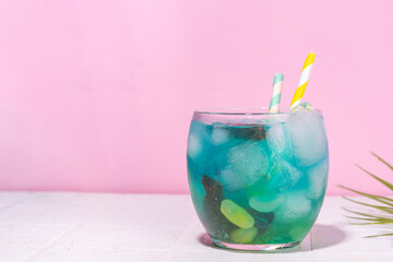 Wall Mural - Funny Fish bowl mocktail. Cold blue colored sour lemon Fishbowl Cocktail with rum, liqueur, citrus juice and jelly fish and stones candy 