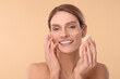 © New Africa - Woman blending foundation on face with makeup sponge against beige background
