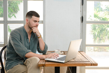 Wall Mural - 1 young freelance working online Casual day lifestyle at coffee shop using laptop computer handsome young man self employed sit and work outside the workplace