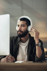 Aufkleber - Brilliant designs inspired by brilliant music. a young businessman writing in a notebook and using a computer with headphones during a late night at work.