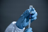 Fototapeta Dmuchawce - Doctor hand in blue gloves holding influenza vaccine for prevention human.Concept fight against human papilloma virus, nurse in laboratory holding a syringe with HPV vaccines for girl and woman.
