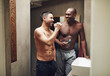 © Flamingo Images - Shirtless gay couple brushing teeth and smiling in bathroom