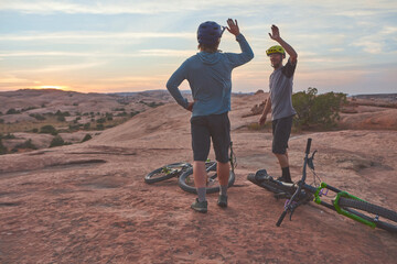 It doesnt get easier, you just get better. two men giving each other a high five while out mountain biking.