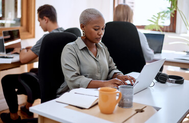 Fototapete - Putting some focus into it. a young businesswoman working on a laptop in an office.