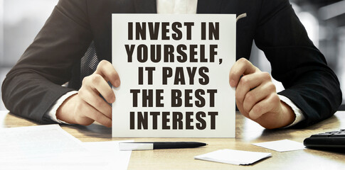 Aufkleber - Businessman holding a white card with text Invest in yourself, it pays the best interest on office background
