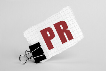 Poster - Piece of paper on a grey background with text PR