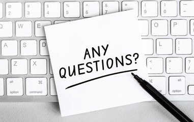 Poster - white paper with text any questions lying on the keyboard