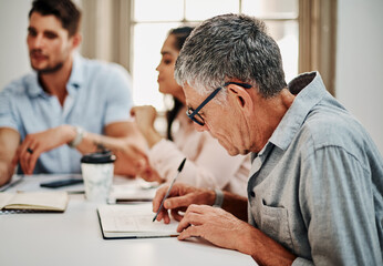 Poster - Record everything, you might need it later. a mature businessman writing notes during a meeting with colleagues in a modern office.