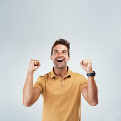 Poster - Thank the stars. Studio shot of a cheerful young man punching the air in excitement while standing against a grey background.