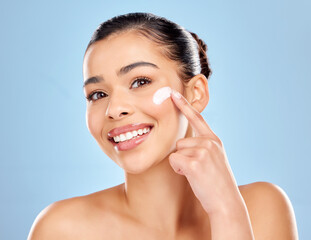 Poster - Its like gold when you find a routine that works for you. Studio portrait of an attractive young woman applying moisturiser on her face against a blue background.