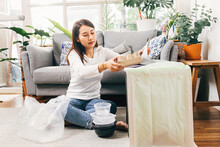 Asian Female Separate Garbage At Home. Young Woman Sorting And Recycling Plastic, Paper, Aluminum Can And Food Container To Trash Bins In Living Room At Apartment. Recycling And Sustainability At Home