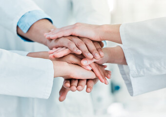 Poster - Improving the world through science in leaps and bounds. Closeup shot of a group of unrecognisable scientists joining their hands together in a huddle in a lab.