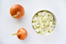Two Onions And Chopped Onion On A White Plate. Onion On A White Background.