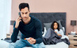 © N F/peopleimages.com - Expert care is a call away. a young man using a smartphone and thermometer while recovering from an illness with his wife at home.
