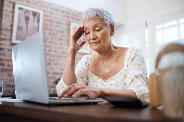 Will the debt ever end. a senior woman looking stressed while using a laptop at home.