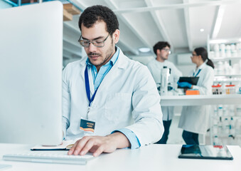 Poster - Doing more research until he reaches a solid conclusion. a young scientist working on a computer in a lab.