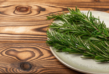 Dried rosemary in a bowl and branches of fresh rosemary on a vintage brown wooden background. Spicy spices for cooking meat and fish. Recipe. Fresh rosemary herb. Place for text, space for copy.