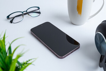 Aufkleber - Phone placed beside office items like a headset, plant, glasses, and a coffee mug. Productivity and modern technology in a work environment composition