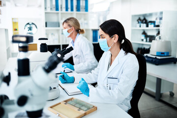 Poster - Getting stuck right in to some lab work. a young scientist working in a lab with her colleague in the background.