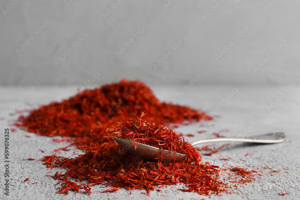 Spoon with pile of saffron on grey grunge background