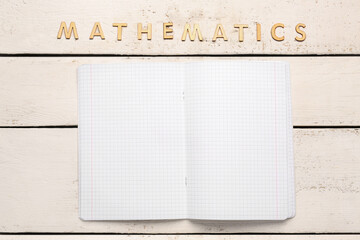 Blank copybook pages and text MATHEMATICS on white wooden background