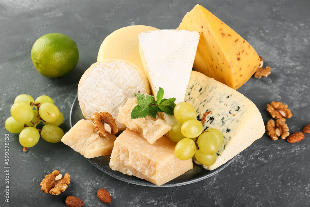 Plate with different types of cheese on green background