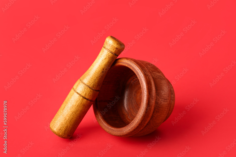 Wooden mortar and pestle on red background