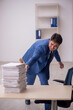 © Elnur - Young male employee unhappy with excessive work in the office