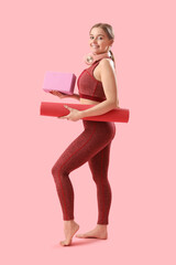 Wall Mural - Sporty young woman with mat and block for yoga on pink background