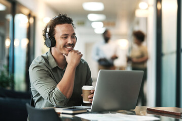 Wall Mural - Listening is part of the planning process. a young businessman sitting in the office and wearing headphones while using his laptop for a virtual meeting.