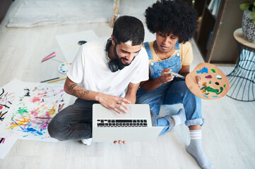 Poster - We decided to stay in and take an online art class. a young couple using a laptop while painting at home.