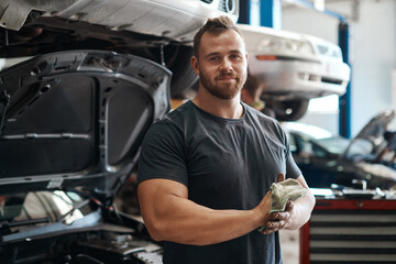 Making sure youre safe and secure on the road. a mechanic using a cloth to wipe his dirty hands.