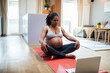 © Baba Images - Young pregnant latina woman meditating at home wihle using a laptop