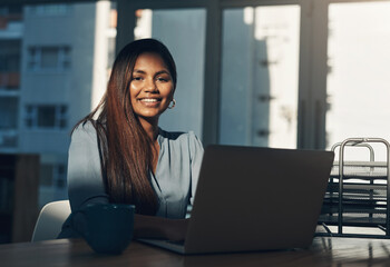 Poster - Heres to another day of hustling. Portrait of a young businesswoman using a laptop in an office.