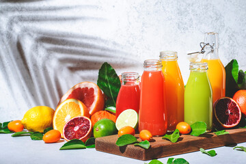 Wall Mural - Summer fruit juices and smoothies, food background. Mix of different whole and cut fruits: orange, grapefruit, lime, tangerine with leaves and bottles with drinks