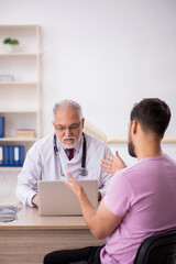 Wall Mural - Young male patient visiting old male doctor