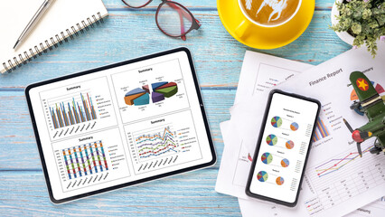 Tablet with charts and reports on office desk workplace. Top view flat lay.