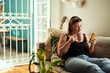 © C Malambo/peopleimages.com - Alone time just got more social. a young woman having coffee and using a smartphone on the sofa at home.