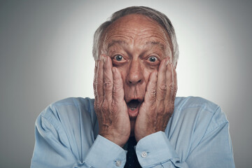 Wall Mural - Im getting too old for surprises. a senior businessman standing against a grey studio background with his face in his hands and looking shocked.