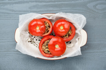 Uncooked stuffed tomatoes with minced beef, bulgur and mushrooms in baking dish on grey wooden table, top view