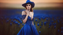 Woman In A Blue Dress And With Blue Hat In The Field With Flowers. Generative AI Image.