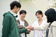 © bongkarn - Image of a group of cheerful Asian college students putting their hands together
